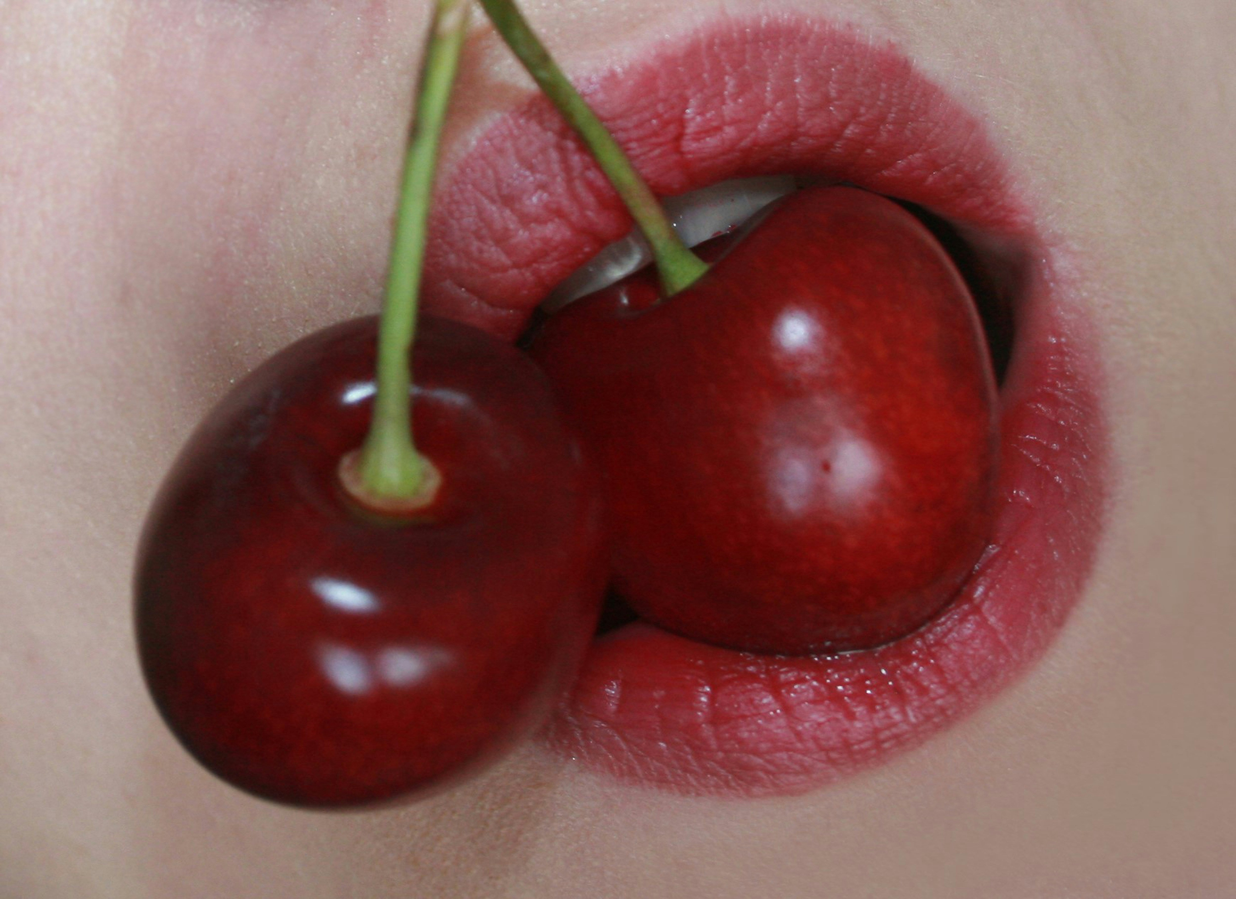 Woman wearing blushed cherry red lipstick, representing the spring-summer 2025 makeup trend