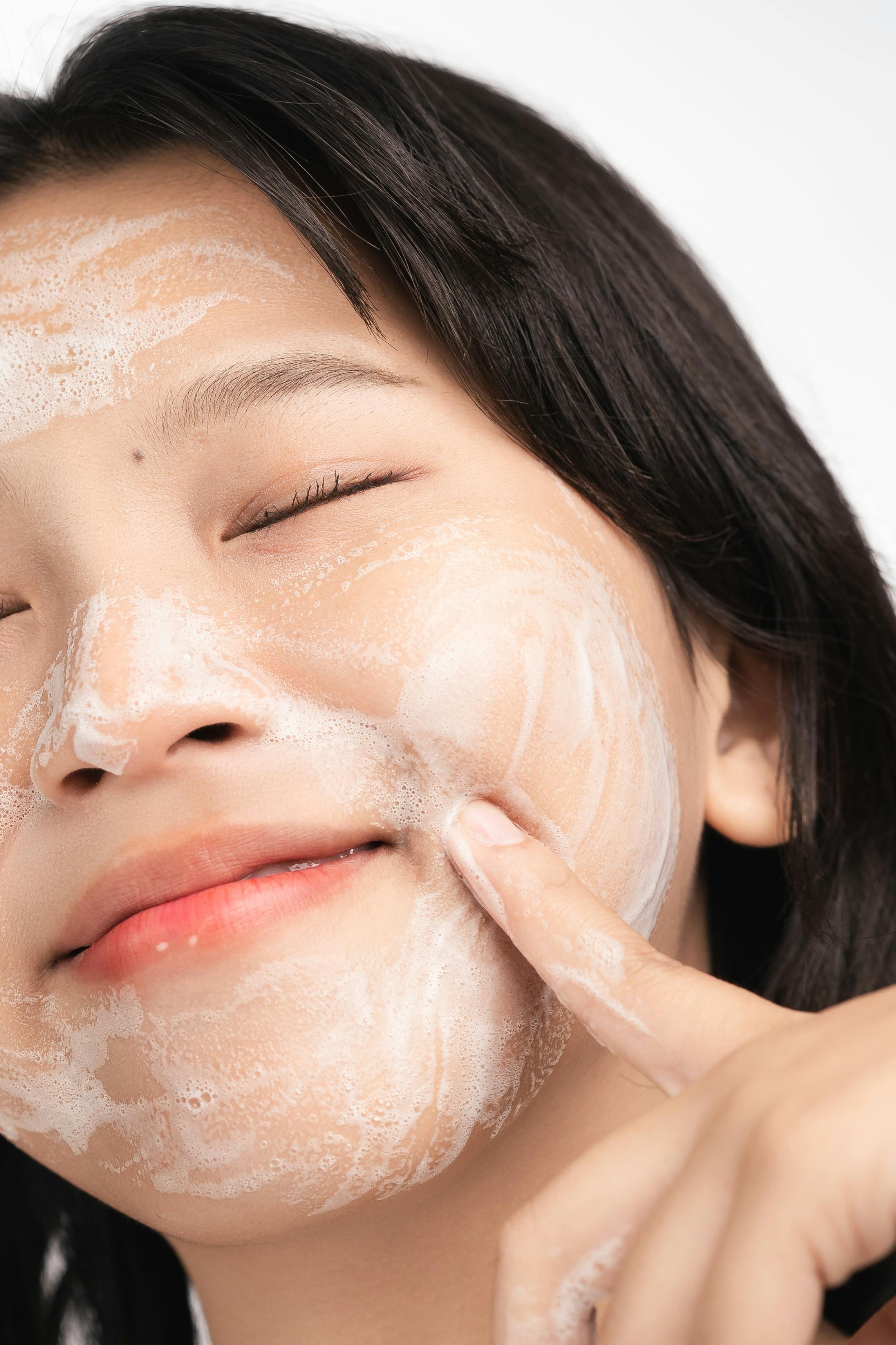 Happy woman cleanses face to achieve glass skin with K-Beauty routine