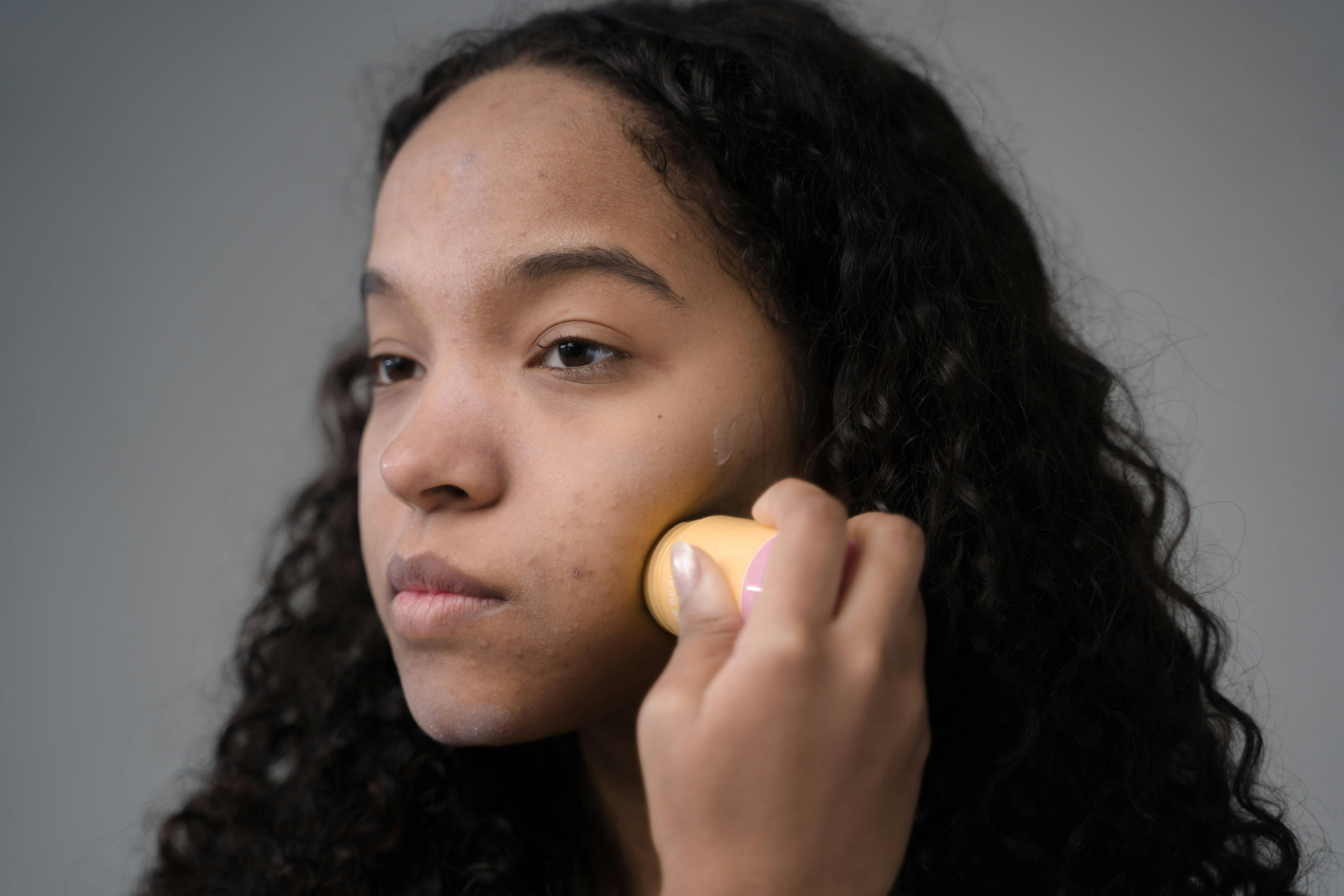 Woman applying skincare and makeup, following an ideal makeup routine for ance prone skin