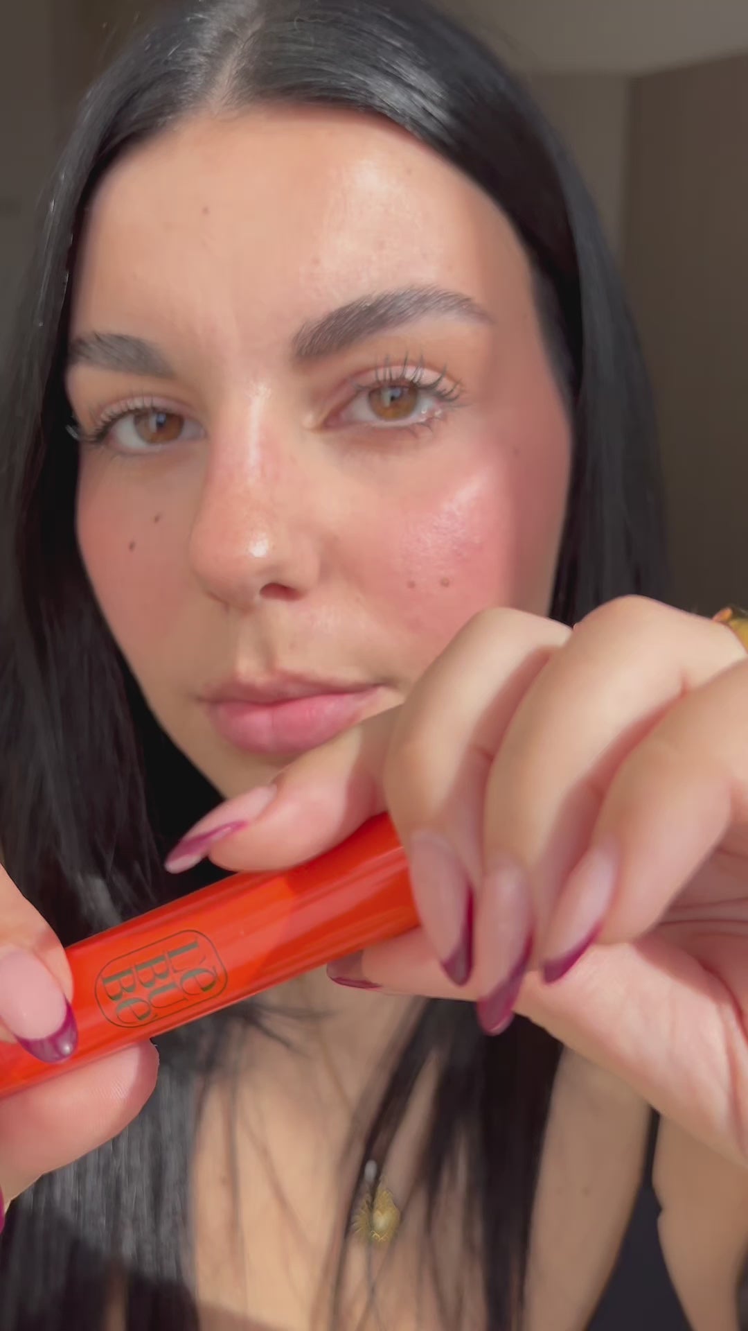 Load video: Woman applying a 2 in 1 vegan blush and lipstick on her cheeks and lis, from Lebubè natural hybrid cosmetics made in Italy