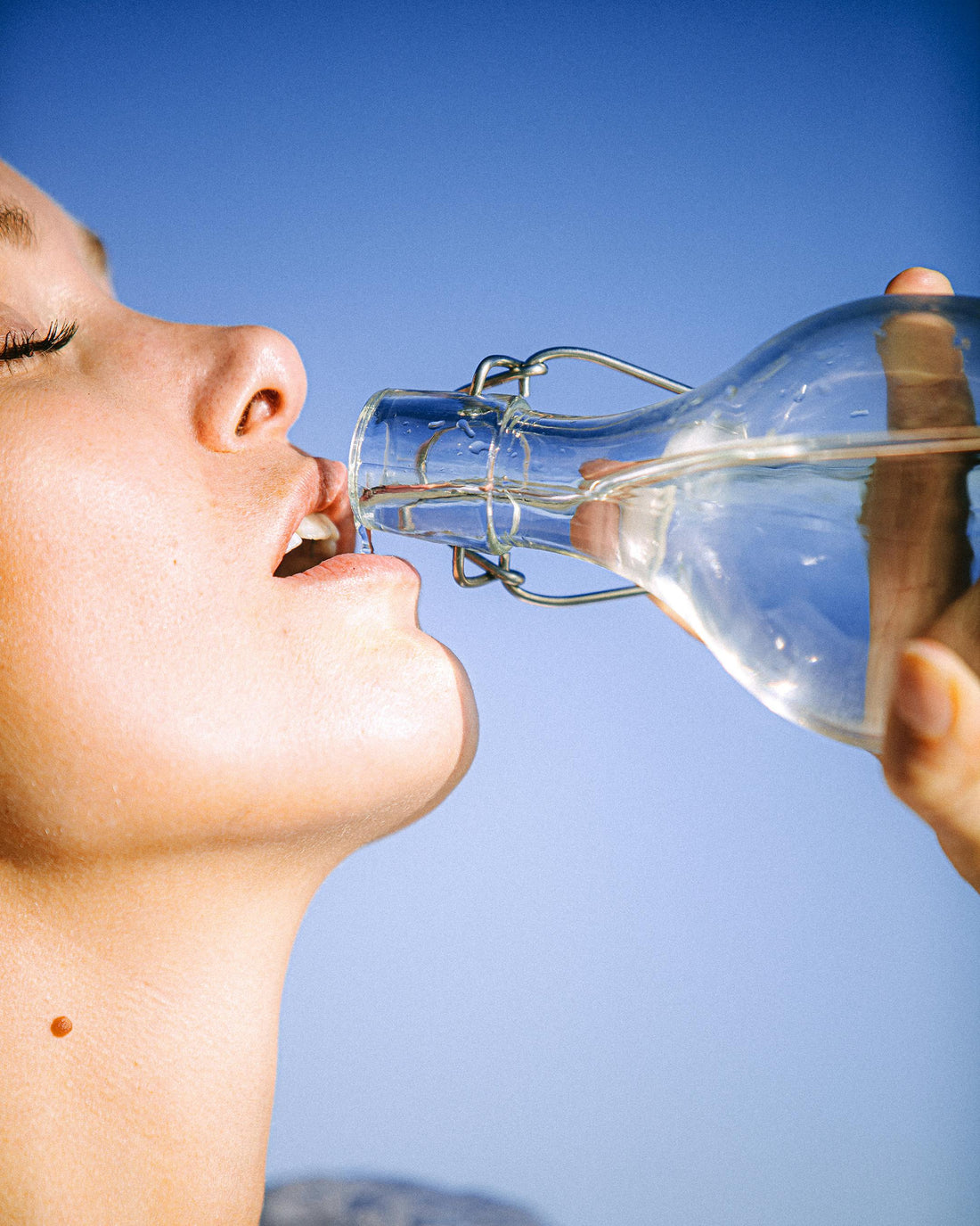 A woman drinking water, symbolising the relation between beauty industry and water