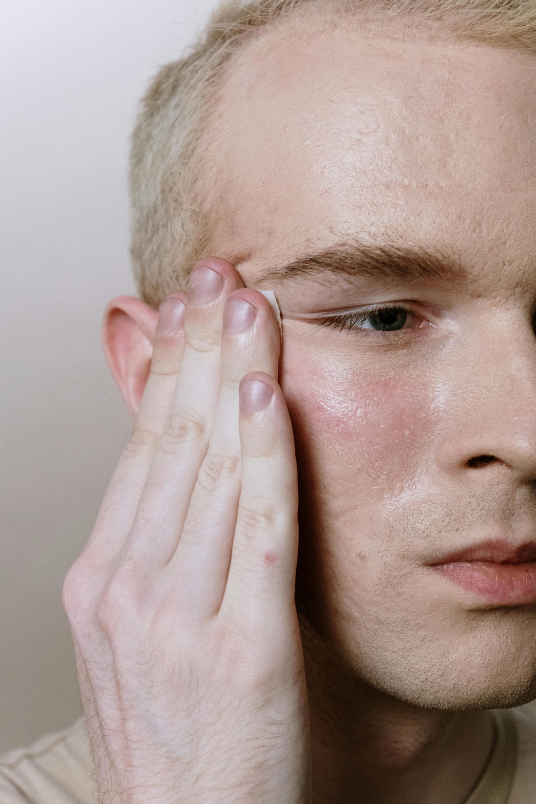 Confident man applying skincare-infused makeup, showcasing modern holistic beauty approach.