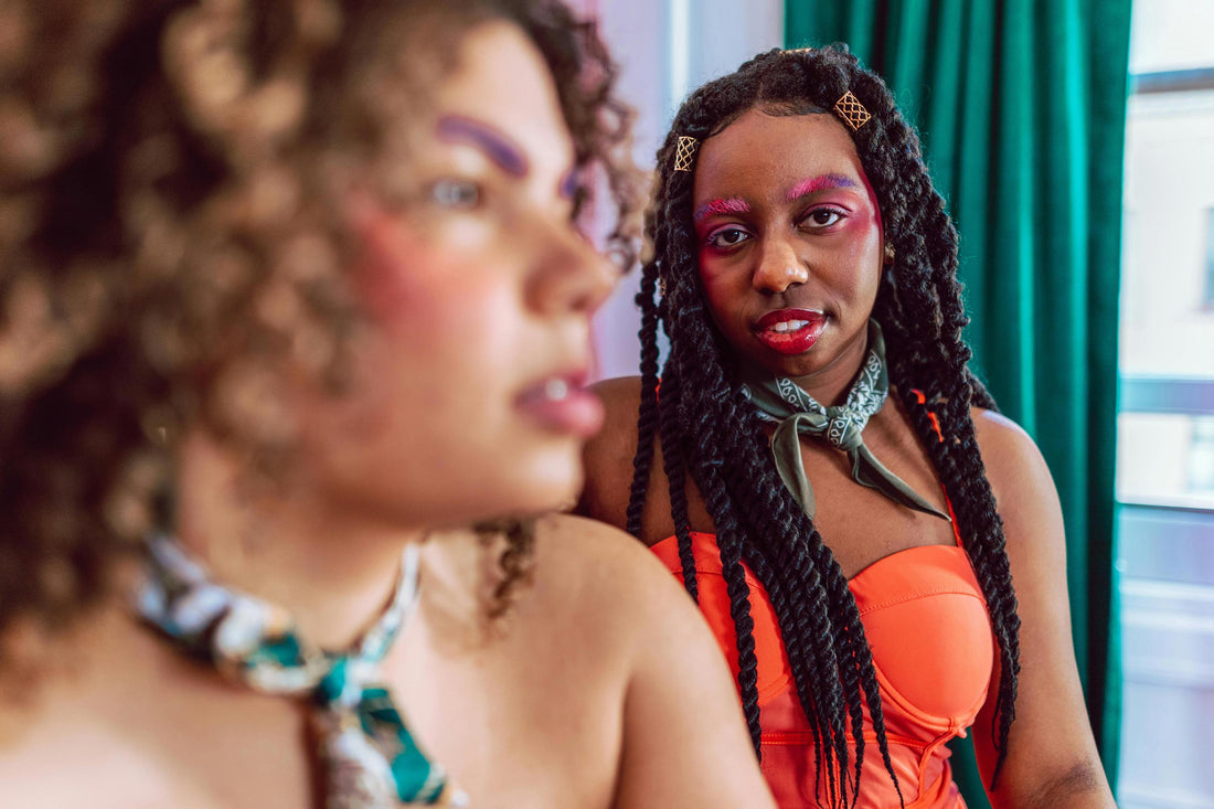 Two young women with natural hair and colourful makeup, showcasing 100% vegan beauty look