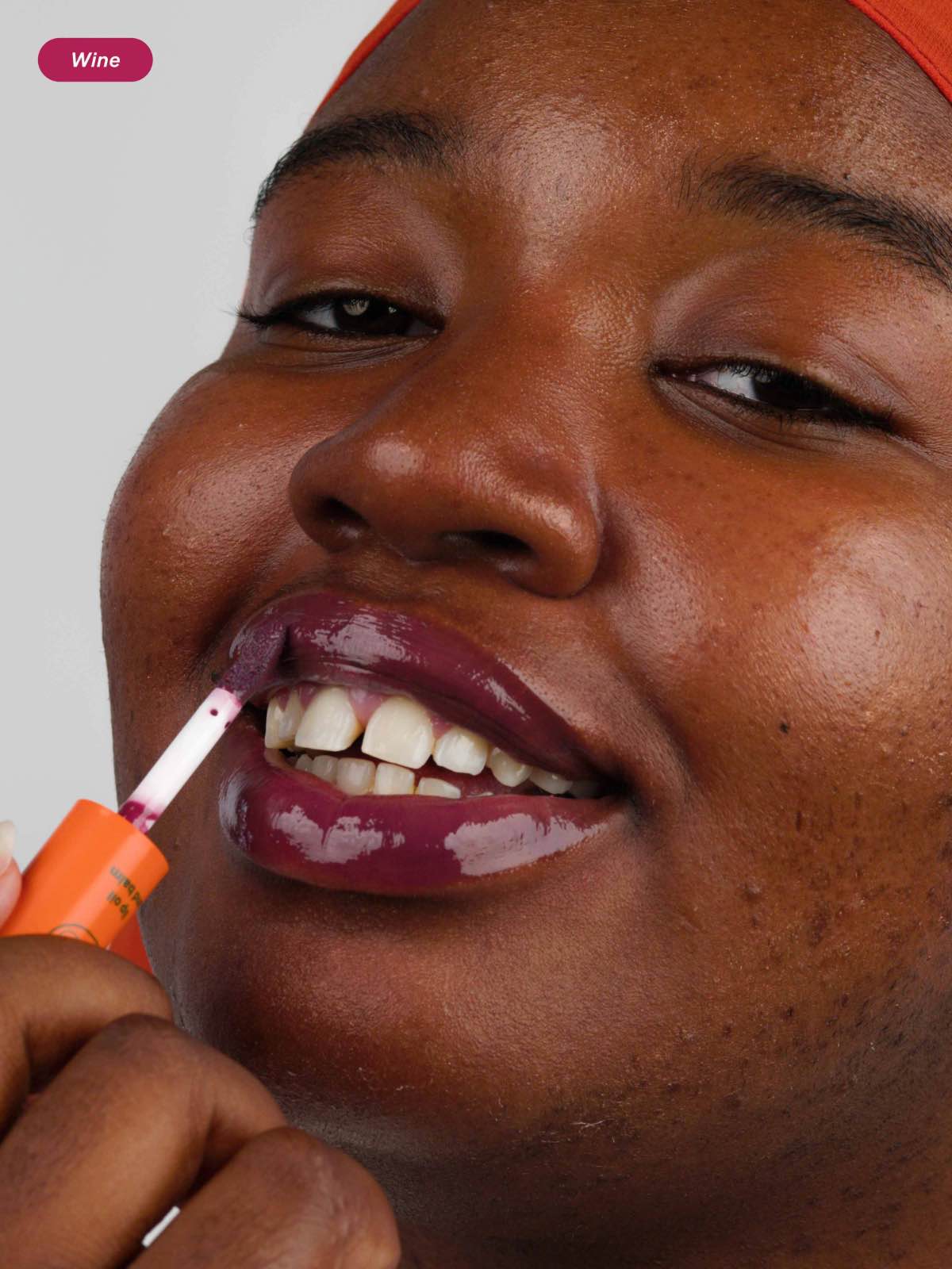 Woman applying the Wine shade of the tinted hydrating lip oil with glossy finish from Lebubè Halal and vegan hybrid cosmetics