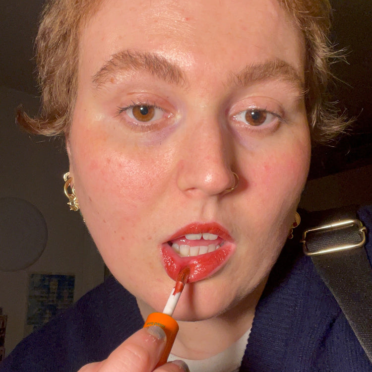Woman applying Lebubè vegan tinted hydrating lip gloss with hyaluronic acid, which doubles as a natural nourishing lip balm
