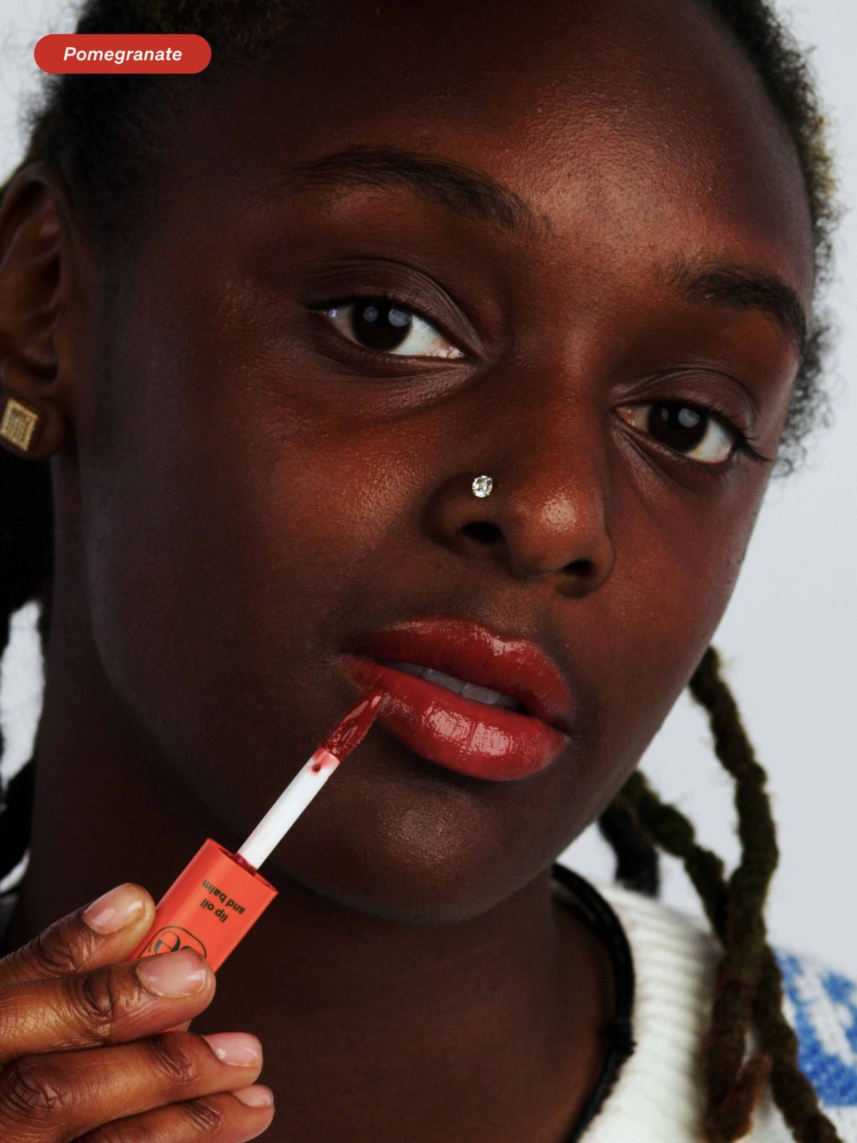 Woman applying the Pomegranate shade of Lebubè natural lip gloss and hydrating lip balm from Lebubè Halal hybrid cosmetics