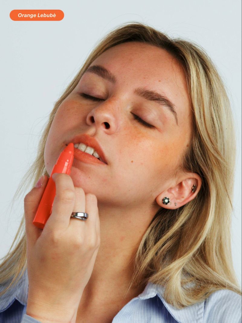 Woman applying the 2 in 1 blush and lipstick in Orange: perfect for summer, sun-kissed lips and a natural look