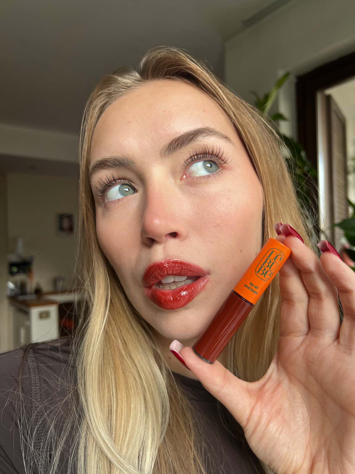 Woman wearing Lebubè plumping tinted lip oil and balm in Pomegranate shade, for hydrated, plumper and softer lips