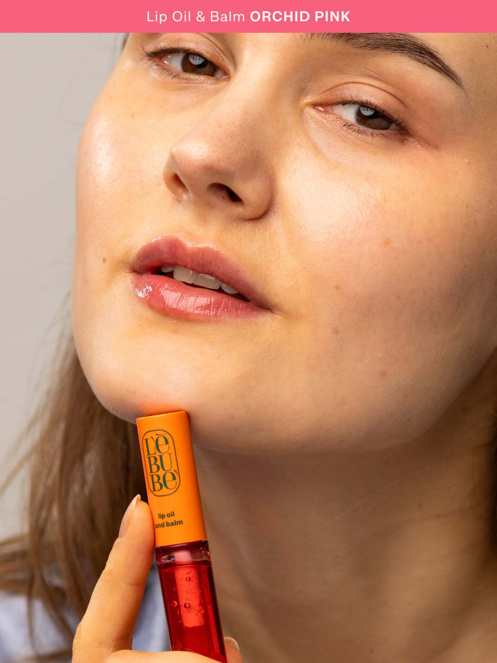 Woman applying the Halal, natural, glossy and hydrating lip balm in Orchid Pink, hydrating peptide lip treatment for dry lips