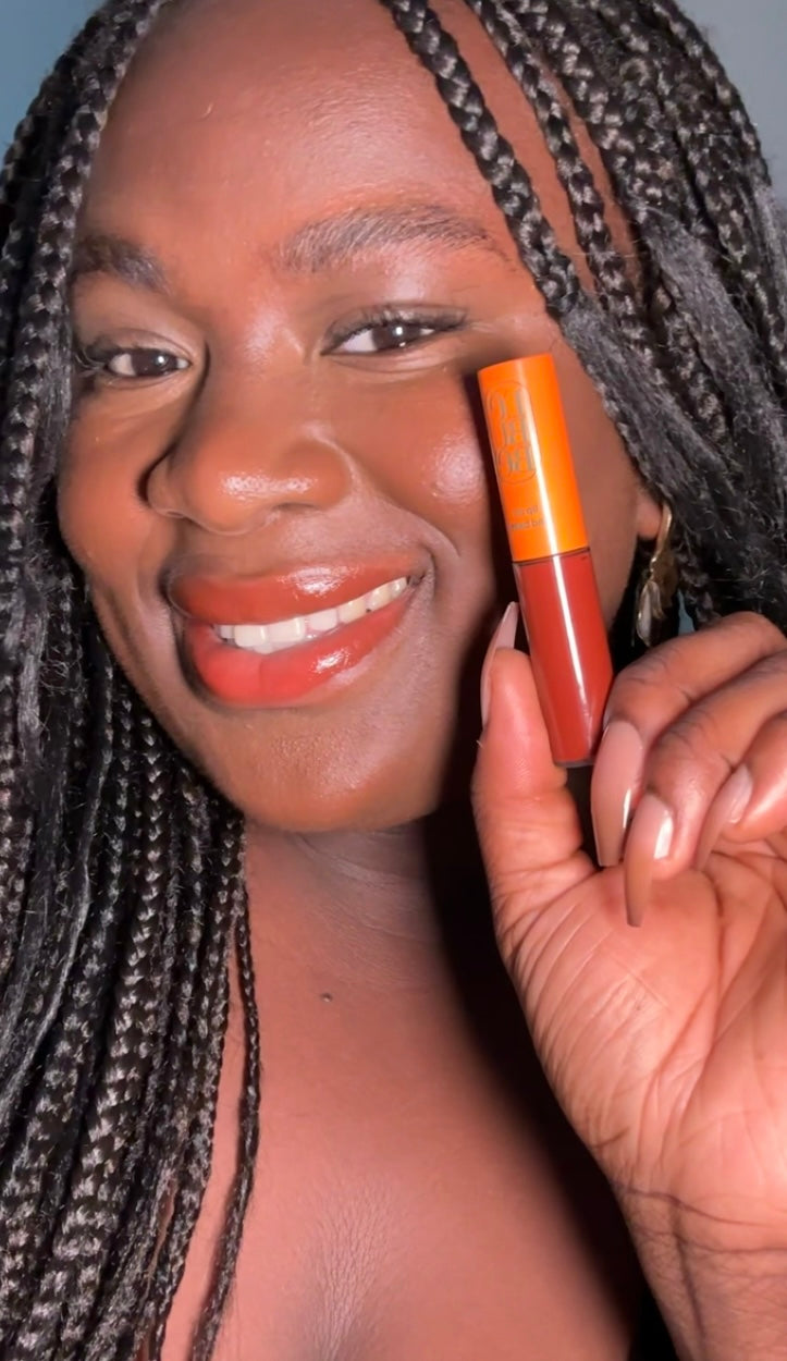 Woman wearing and holding Lebubè Tinted Lip Oil & Lip Balm close to her face. Vegan, plumping, natural, with hyaluronic acid