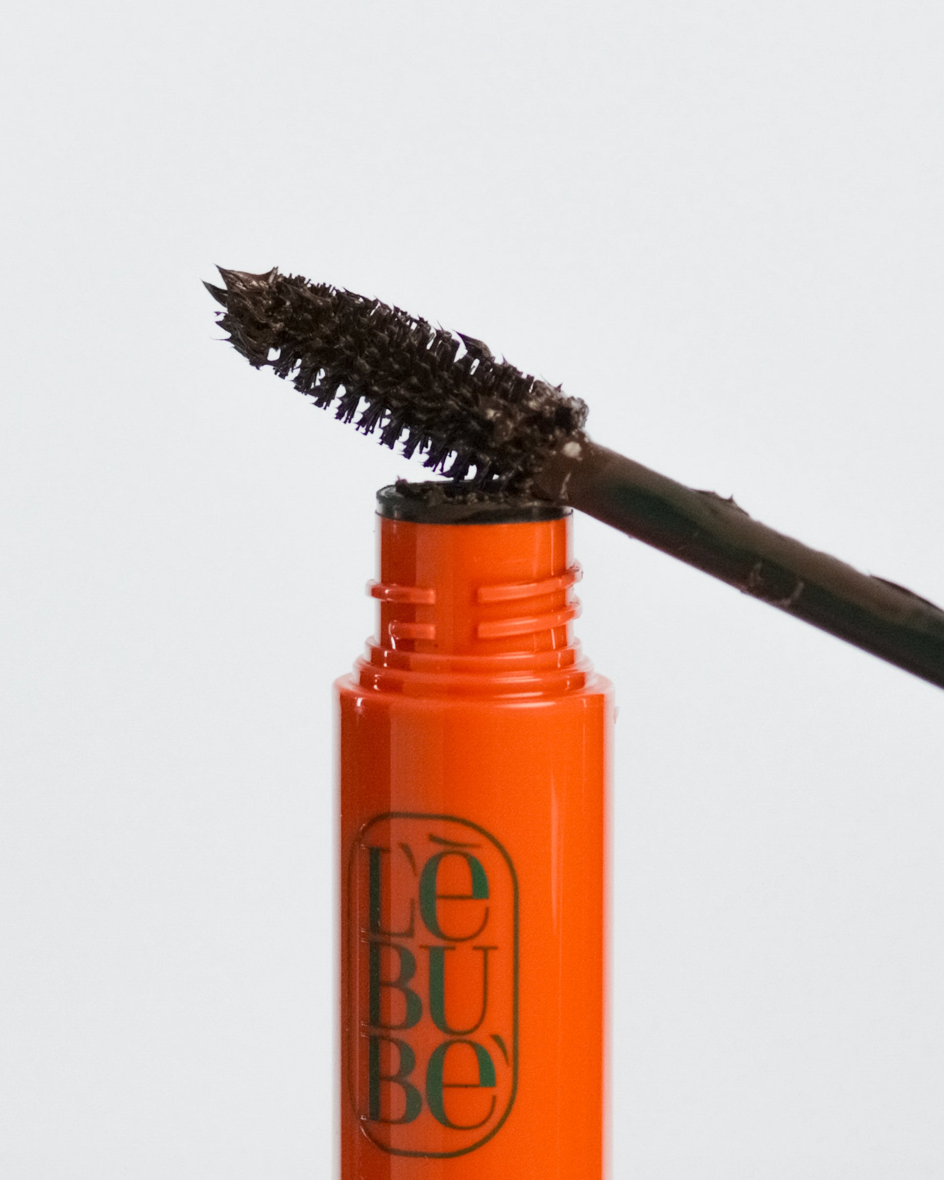 Lebubè plant-based brown mascara for naturally defined lashes. Brush zoomed in, resting on the tube. From Lebubè hybrid cosmetics