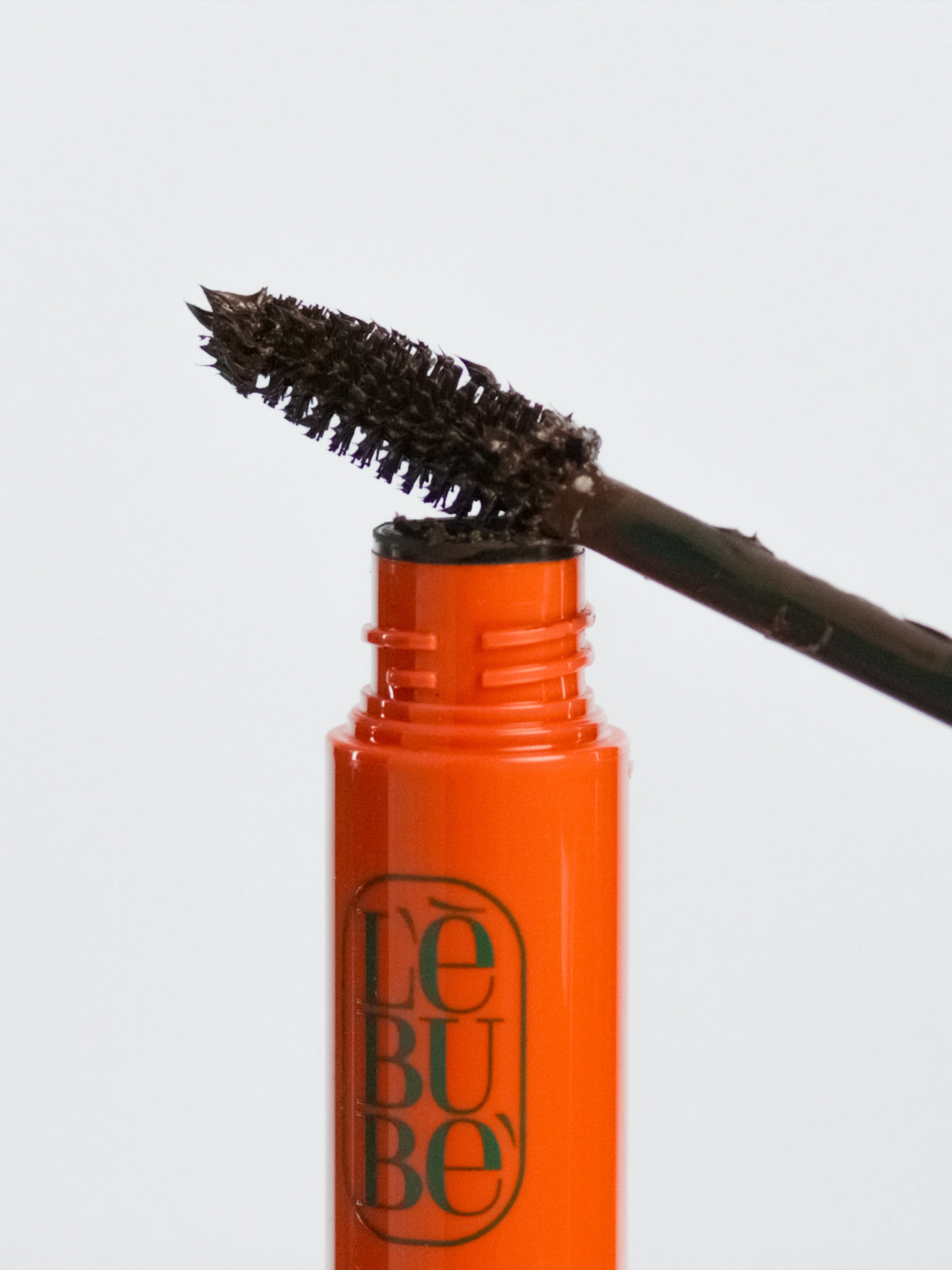 Lebubè plant-based brown mascara for naturally defined lashes. Brush zoomed in, resting on the tube. From Lebubè hybrid cosmetics