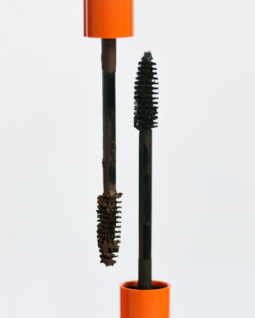 Lebubè plant-based brown and black mascara for naturally defined lashes. Brush zoomed in, resting on the tube. From Lebubè hybrid cosmetics