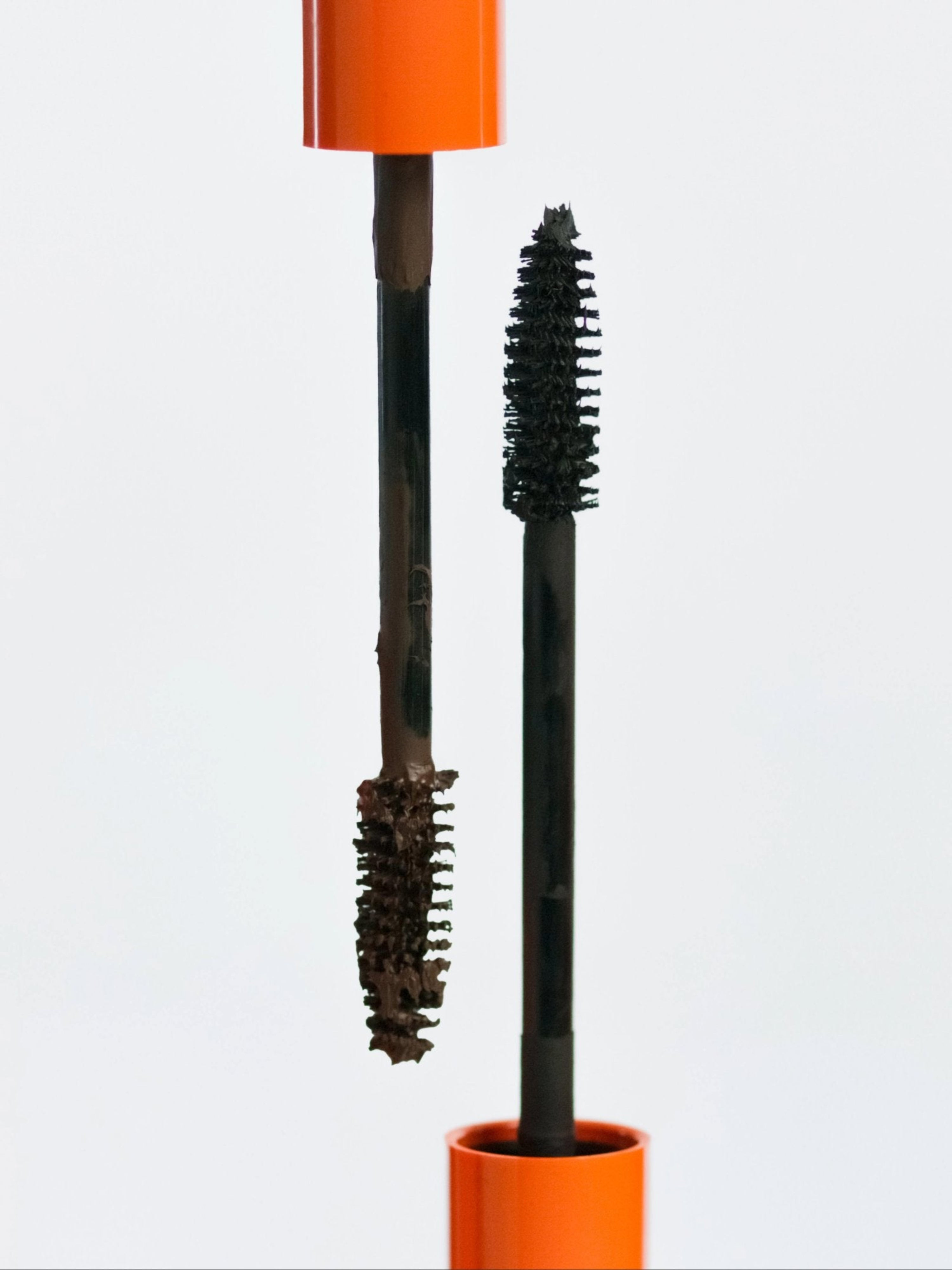 Lebubè plant-based brown and black mascara for naturally defined lashes. Brush zoomed in, resting on the tube. From Lebubè hybrid cosmetics