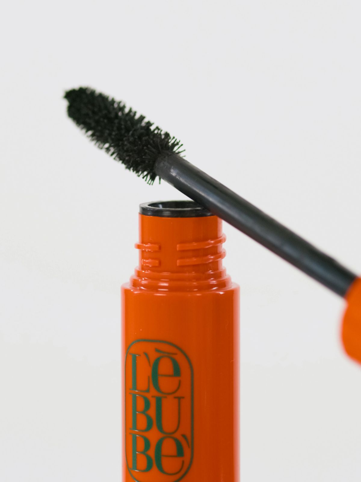 Lebubè plant-based black mascara for naturally defined lashes. Brush zoomed in, resting on the tube. From Lebubè hybrid cosmetics