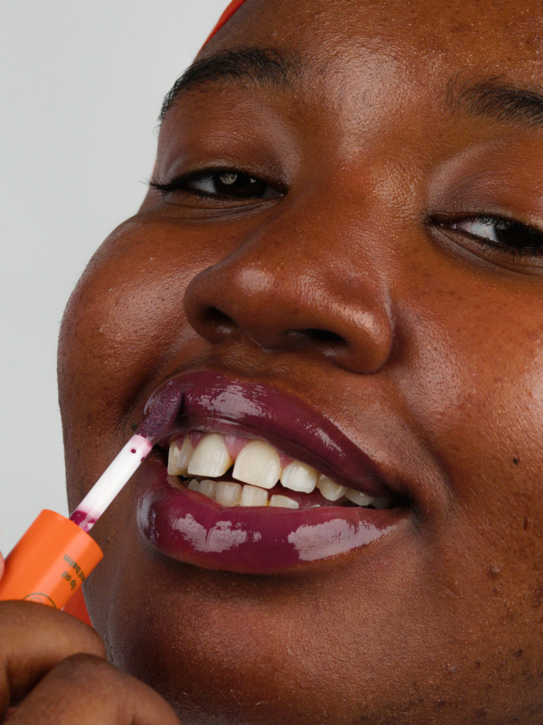 Woman applying the Wine shade of the tinted hydrating lip oil with glossy finish from Lebubè Halal and vegan hybrid cosmetics