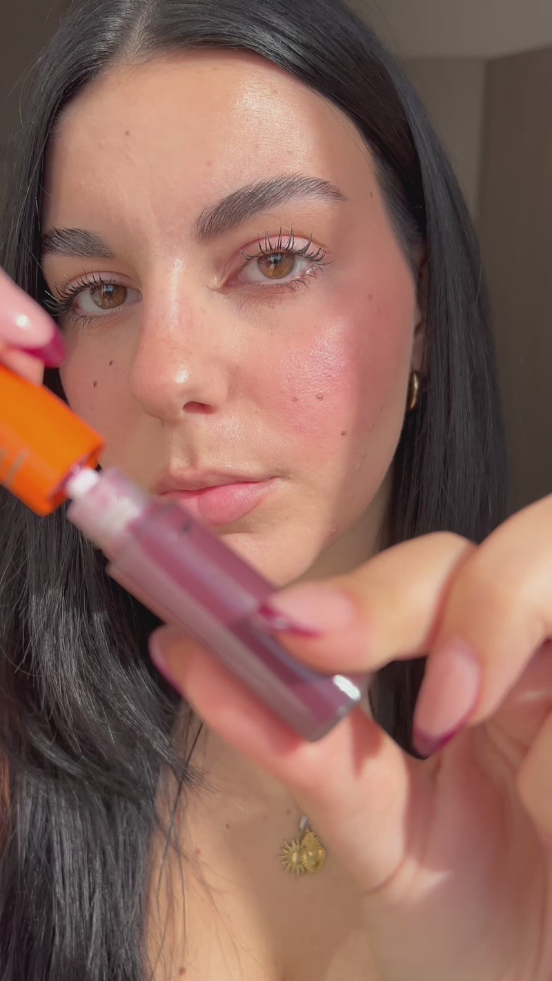 Woman applying Lebubè plumping lip oil with hyaluronic acid in Wine shade on her lips, making them smoother and plumper