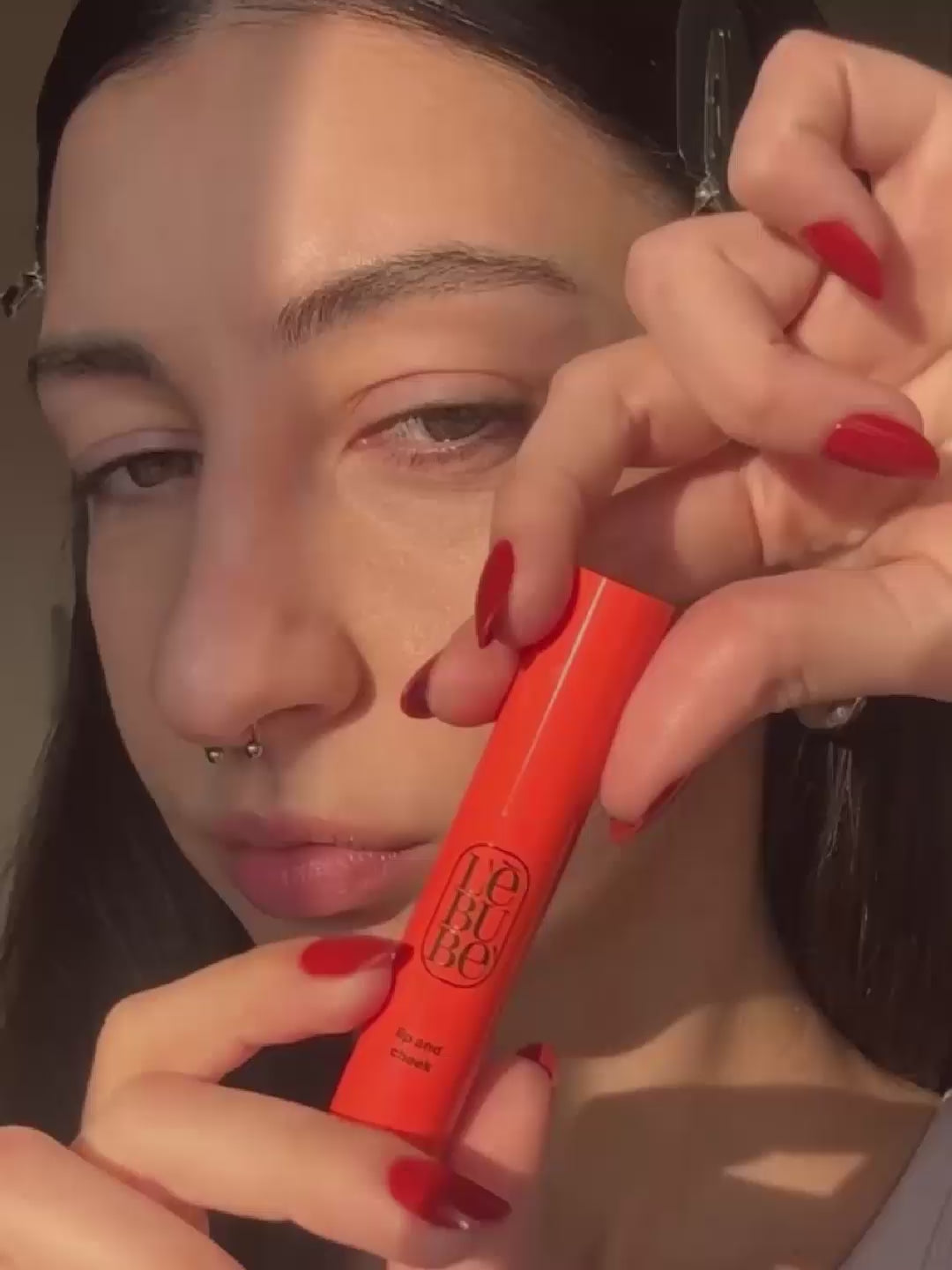 Load video: Woman applying Lip and Cheek in Fiery Red, a lipstick + blush crayon from Lebubè vegan makeup with skincare benefits