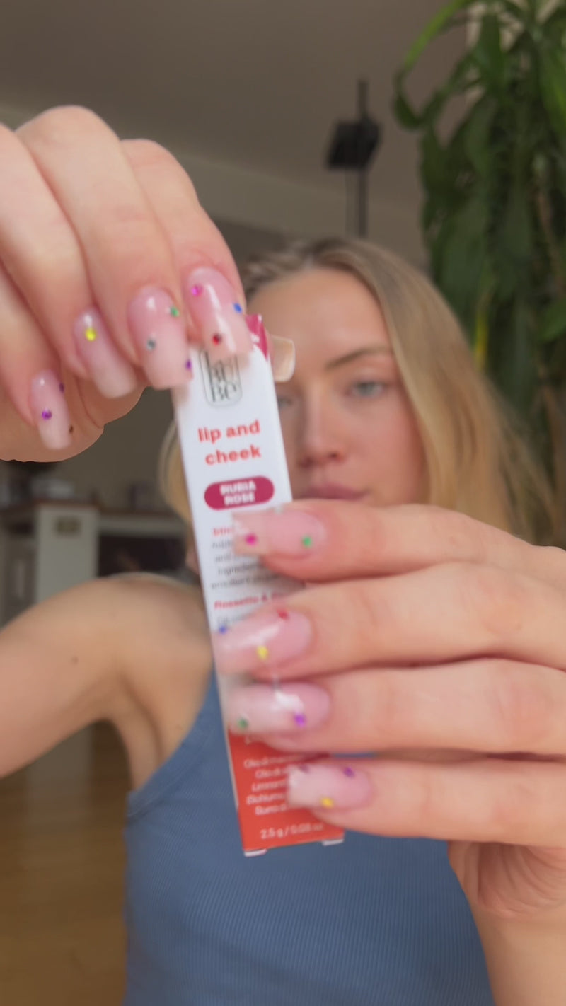 Woman applying Lebubè Lip and Cheek in Rubia Rose, makeup with skincare benefits being a hydrating lipstick and blush in one