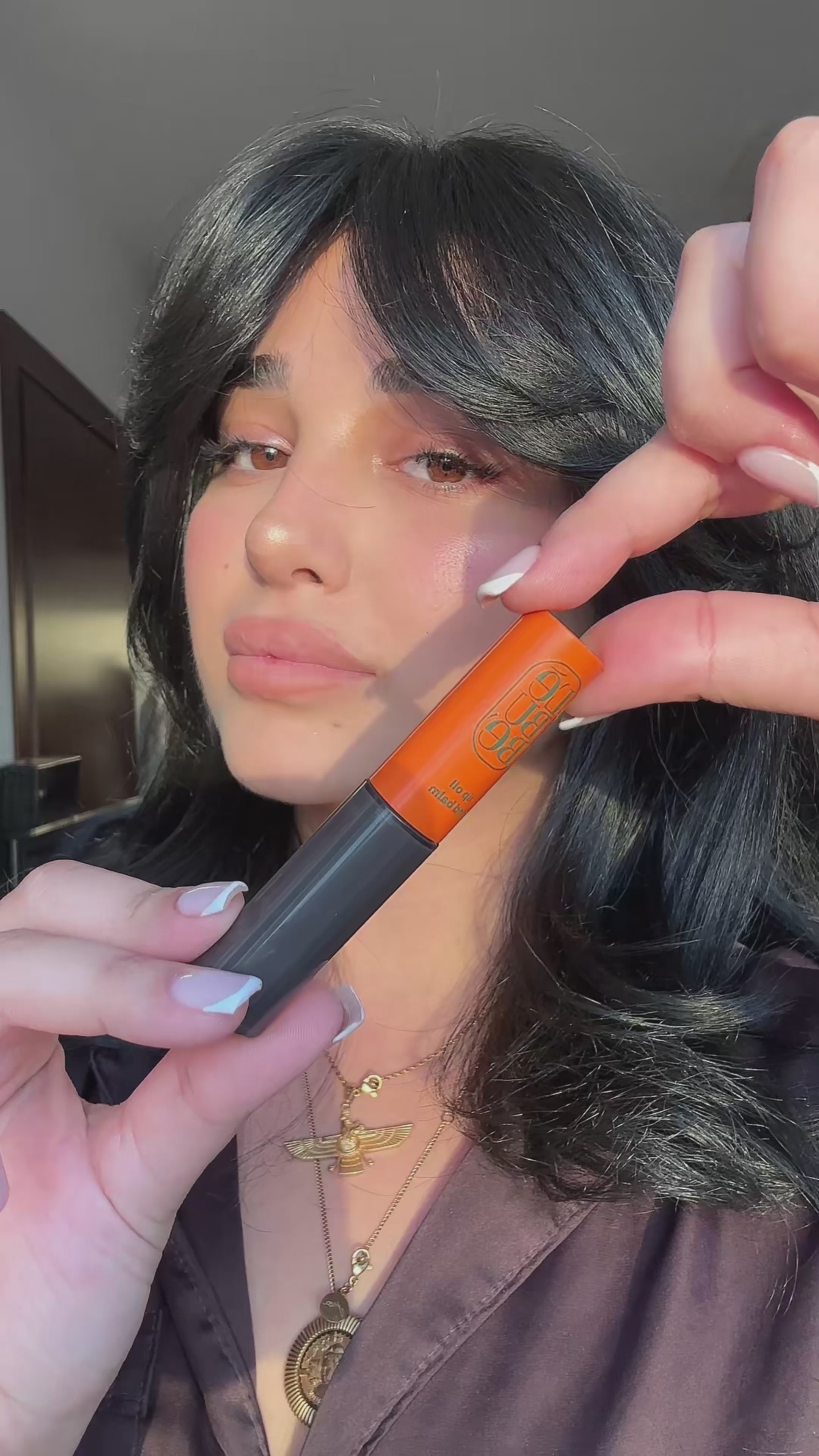 Load video: Woman wearing Lebubè Tinted Lip Oil and Balm in Enigma, a plumping gloss with hyaluronic acid for hydration and nourishment