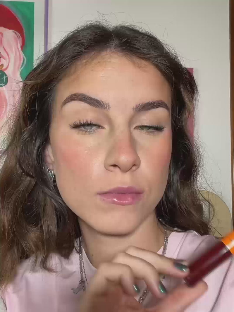 Woman applying Lebubè plumping lip oil with hyaluronic acid in Erotic shade on her lips, making them smoother and plumper