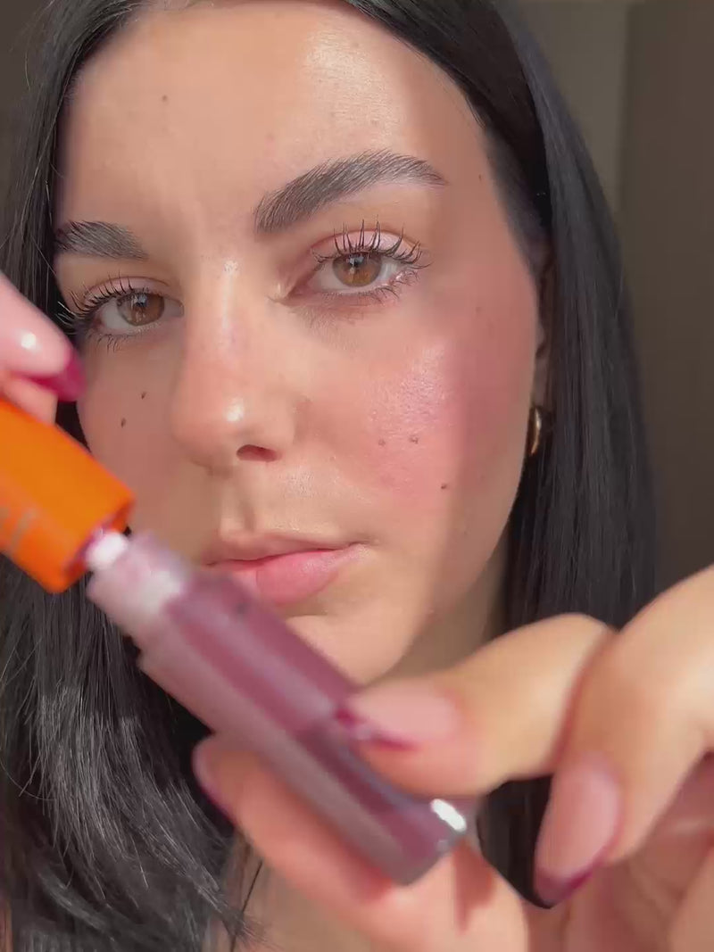 Woman applying Lebubè plumping lip oil with hyaluronic acid in Wine shade on her lips, making them smoother and plumper