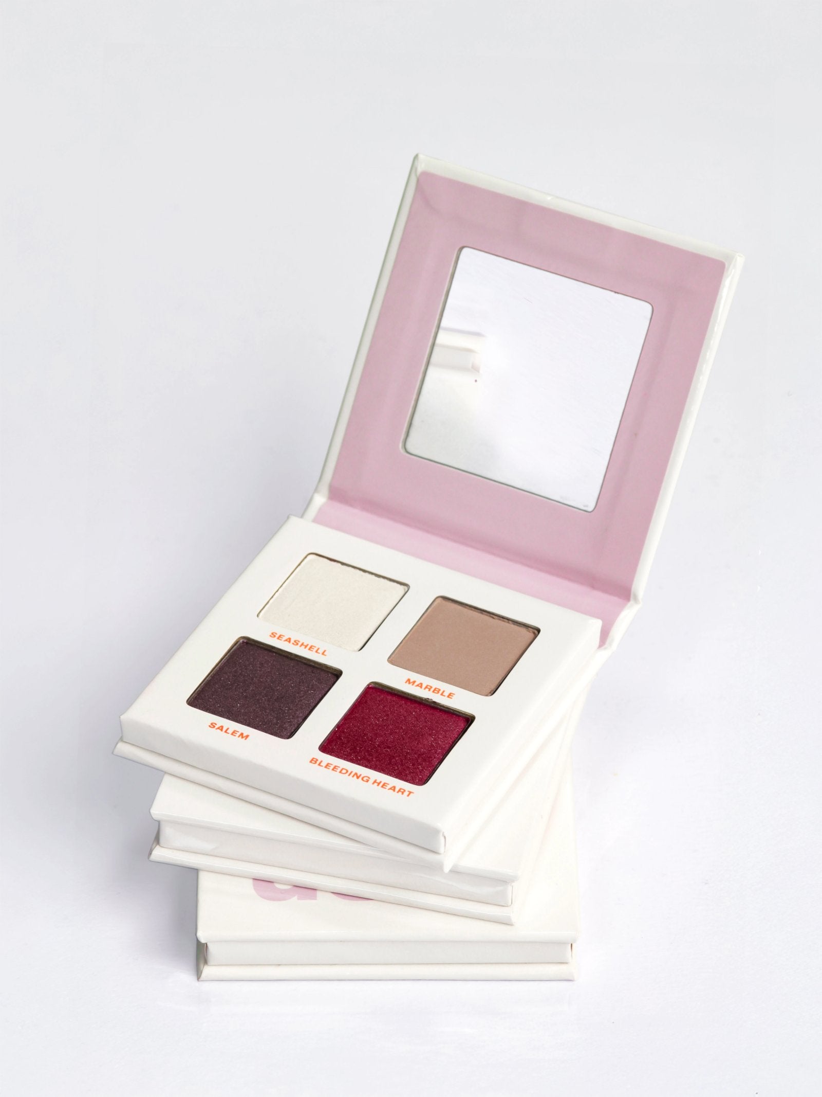 Three stacked DUSK eyeshadow palettes, the top one open showing 4 cool neutral nude eyeshadows in a talc-free vegan formula