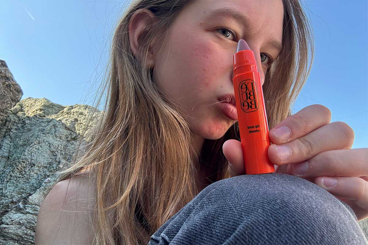 Woman wearing Lebubè Lip and Cheek in Vintage Rose on her hand, a 2 in 1 hydrating blush and lipstick in nude mauve pink